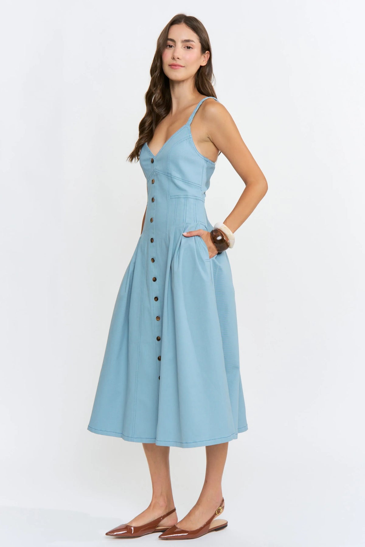 A light blue midi denim dress with v-neckline, button-front detailing, and thin spaghetti straps