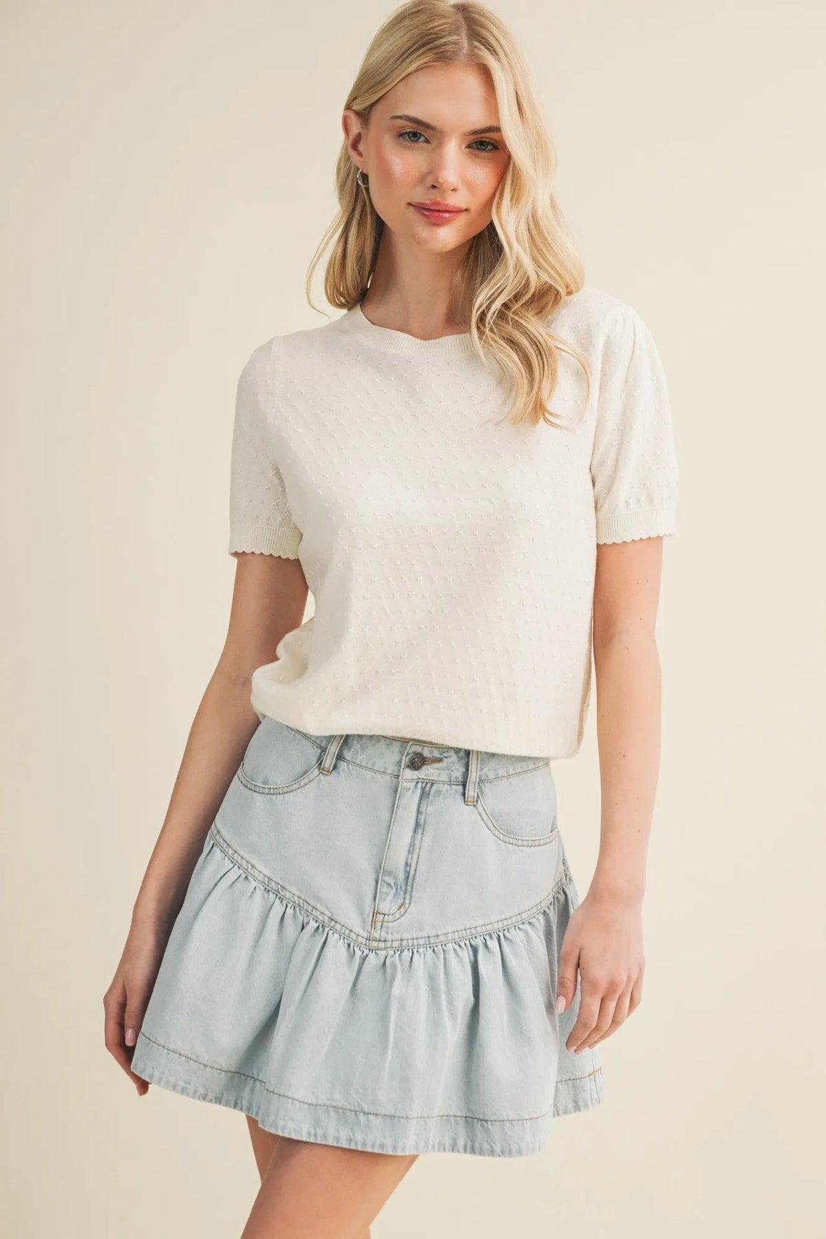 A light blue denim skirt with ruffled hem and front pockets paired with a starburst pointelle puff sleeve top