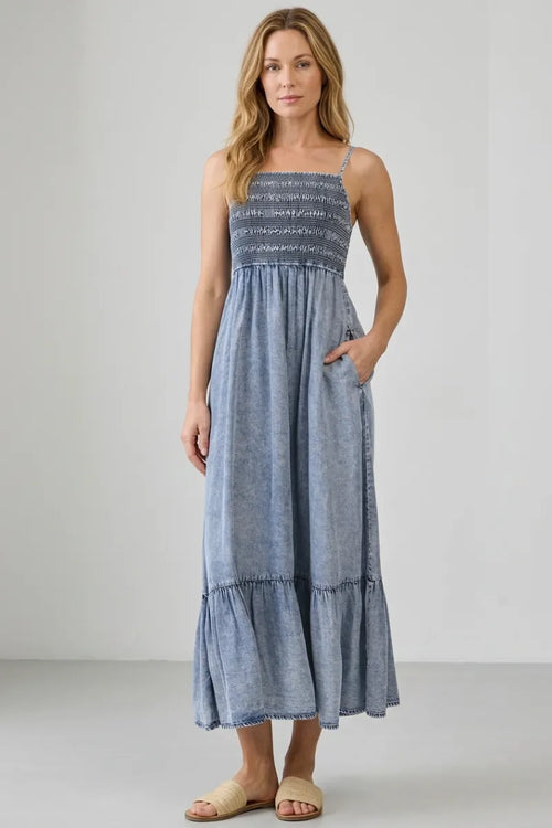 A flowing light blue tencel smocked tiered midi dress with a maxi length and tiered skirt design
