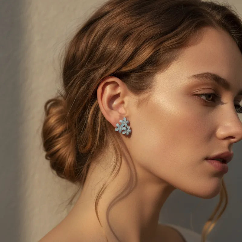 Dainty blue floral blossom stud earrings with light blue layered petals and a subtle metallic finish