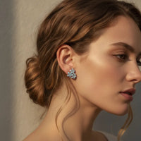 Dainty blue floral blossom stud earrings with light blue layered petals and a subtle metallic finish