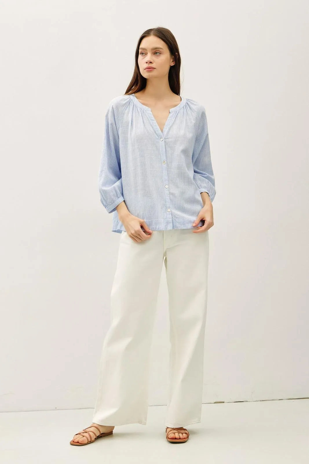 Light blue long-sleeved round neck blouse with gathered neckline and buff sleeve button detail