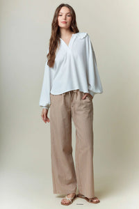 A light blue ribbed blouse with ruffled shoulder details paired with yarn dye stripe elastic pants