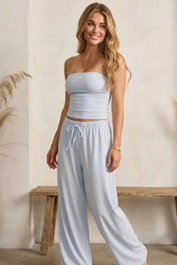 Light blue strapless crop top with relaxed ruched fit and subtle elastic waistband paired with mid rise striped tie waist wide pants