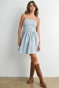 A light blue textured cotton polka dot flare mini dress with thin white strap fit tie straps and a flared skirt