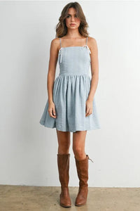 A light blue polka dot flare mini dress with thin spaghetti strap fit and tied white ribbon shoulder details