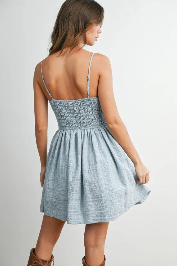 A light blue textured cotton polka dot flare mini dress with thin spaghetti strap fit and a smocked waist