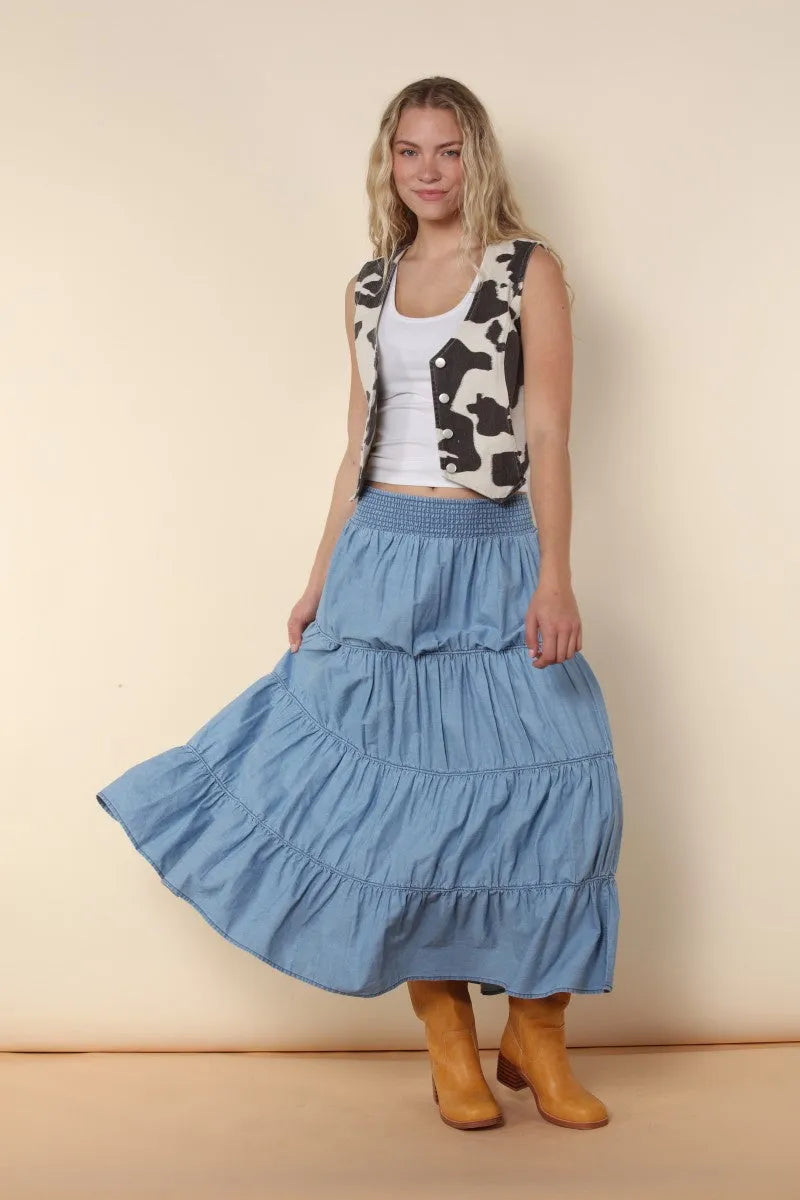 A flowing light blue elastic tiered midi denim skirt with a gathered waistband and ruffled layers