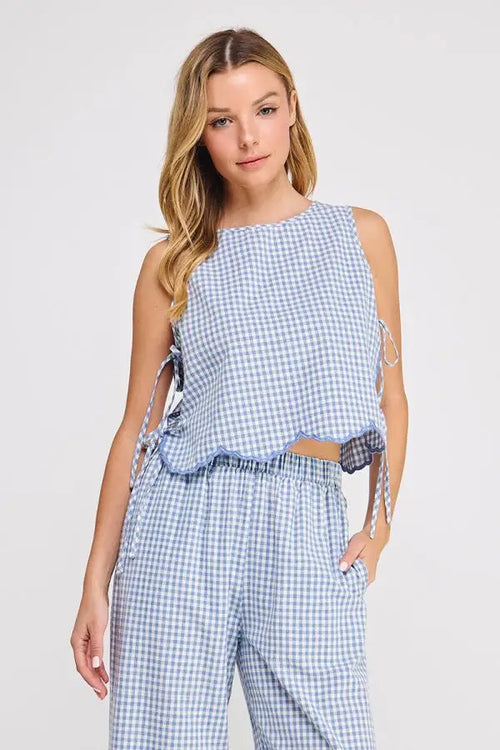 A light blue and white gingham cotton blend sleeveless top with scalloped hem and cotton blend tie sides