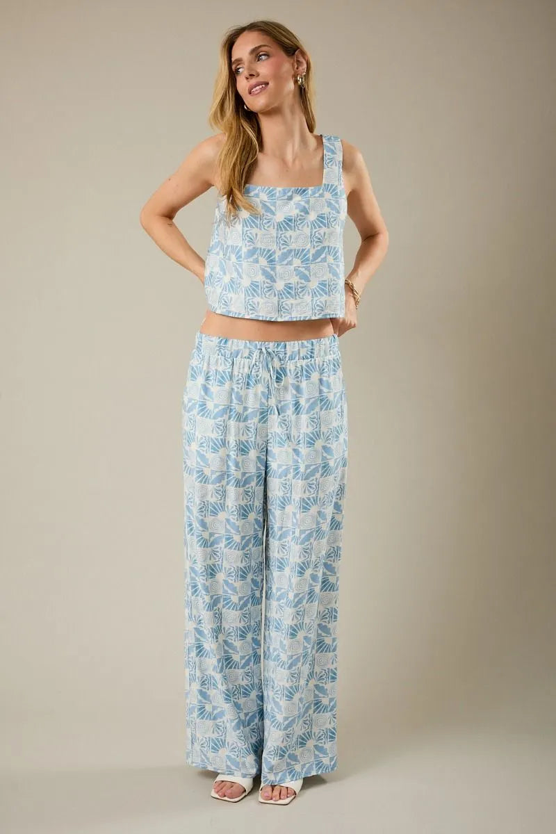 Light blue and white leaf-patterned linen pants with a drawstring waist paired with a sleeveless square neck abstract print top