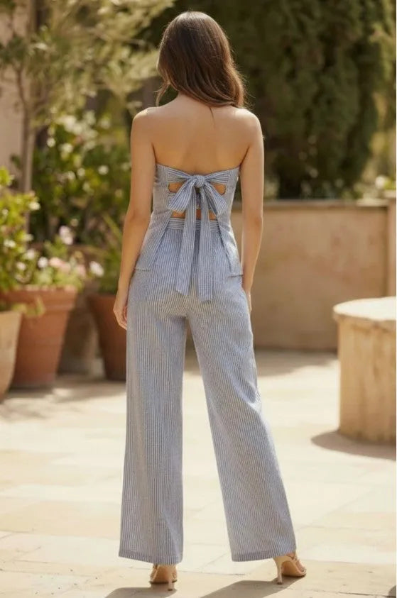 Light blue and white vertically striped strap tube jumpsuit with tie strap back detail in a strapless design