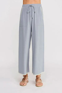 Light blue linen wide leg pant with elastic tie waist and white pom-pom trim along sides and hem