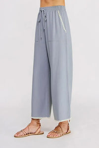 Light blue linen wide leg pants with elastic tie waist and white zigzag trim along side seam and hem
