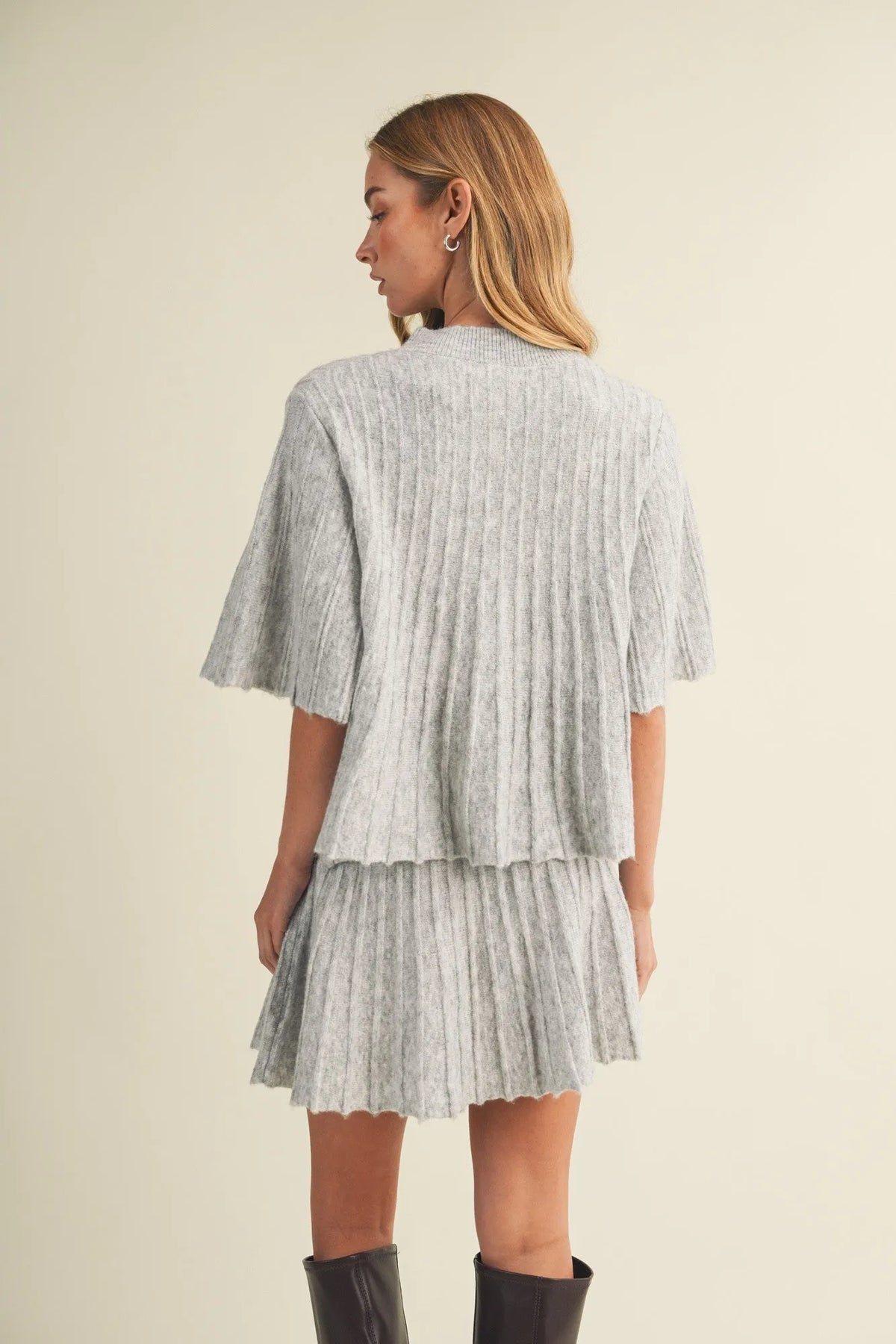 A light gray wide rib knit two-piece outfit with a cropped cape-style top and matching pleated skirt