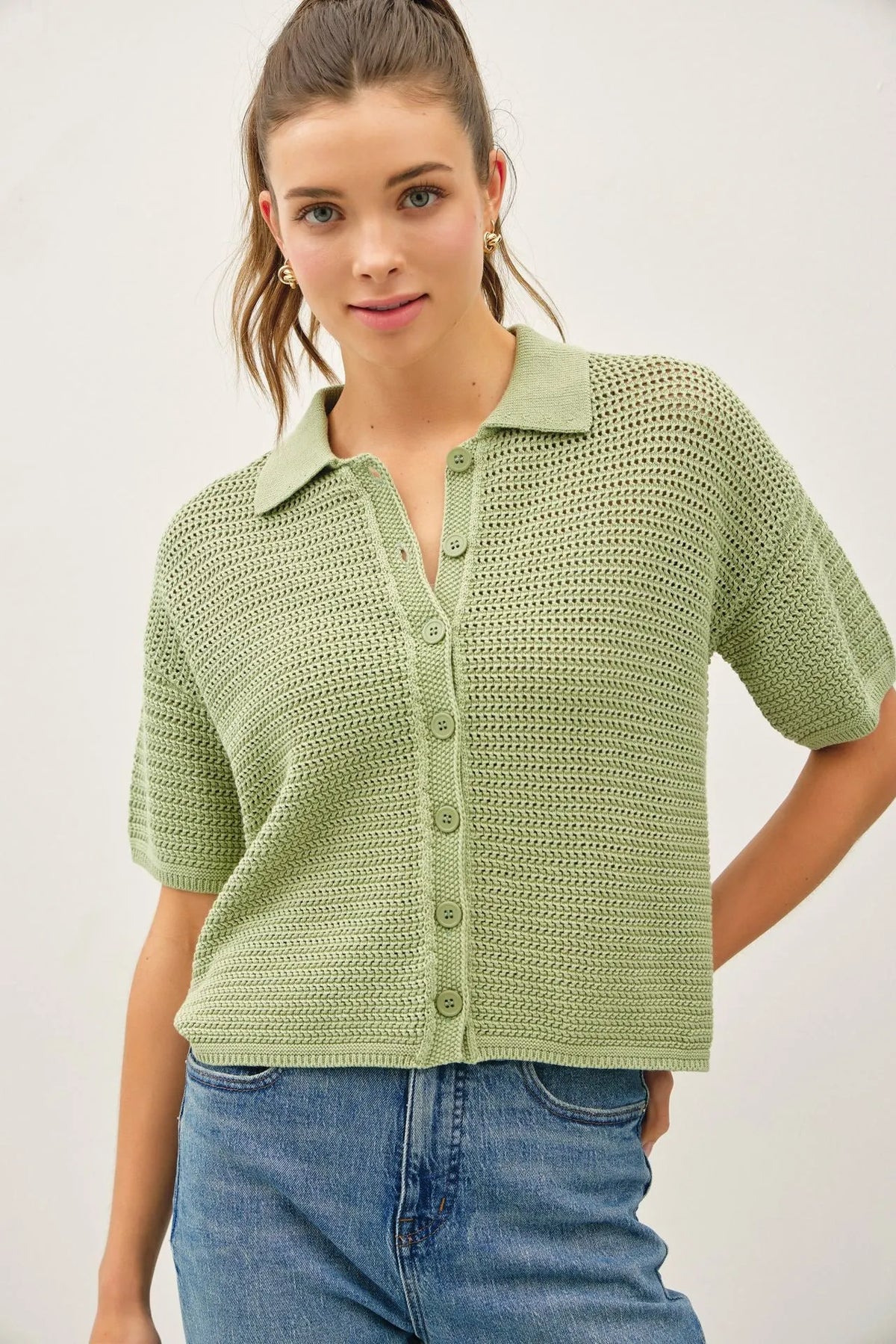 A light green boxy crochet collared short sleeve cardigan with buttons and collar made from knitted fabric