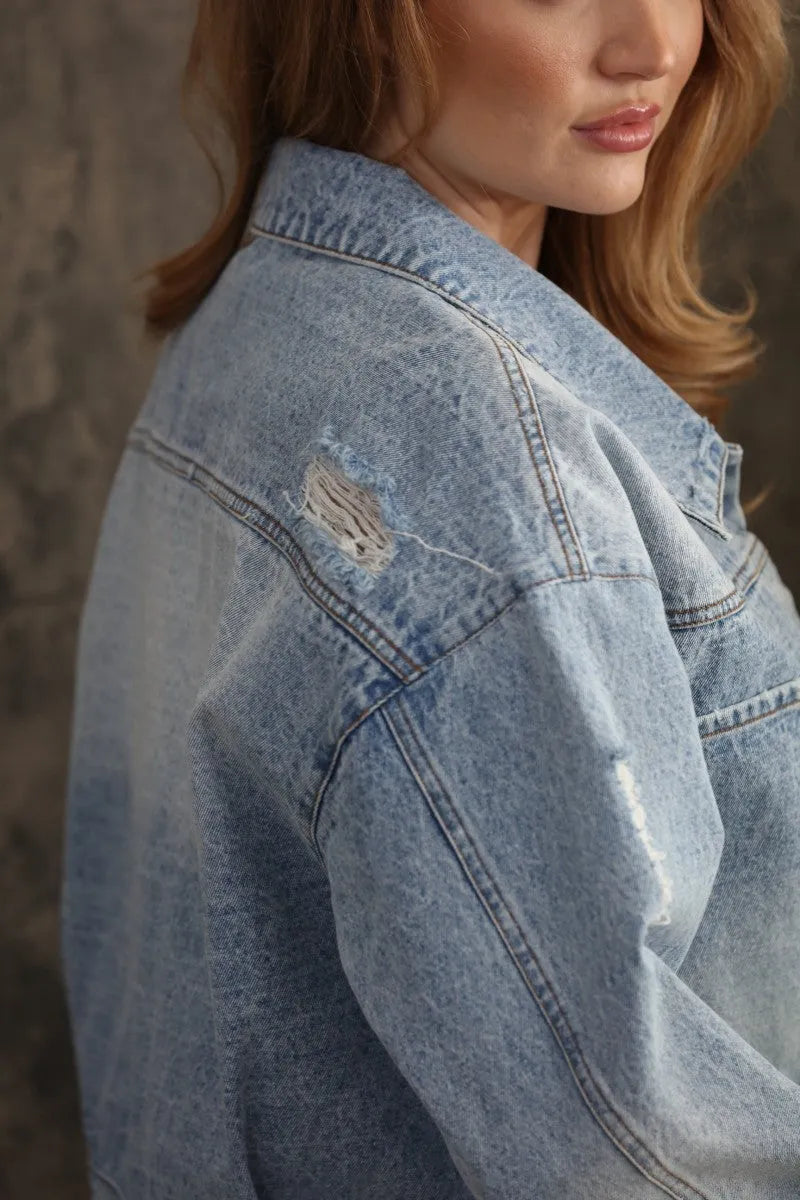 Oversized trucker bow patch denim jacket in light-wash with a distressed patch on the shoulder