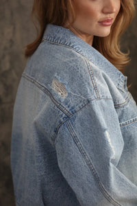 Oversized trucker bow patch denim jacket in light-wash with a distressed patch on the shoulder
