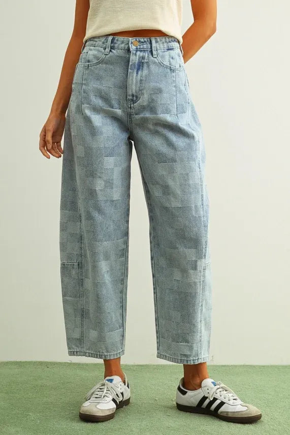 Light-wash denim pants featuring a checker board pattern barrel design with varied patchwork textures and shades