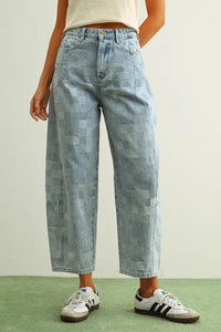 Light-wash denim pants featuring a checker board pattern barrel design with varied patchwork textures and shades