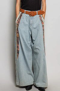 Light-wash relaxed fit pointed denim wide-leg pants with floral side panels and a brown woven belt for women’s boho chic clothing