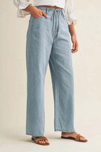 Light-wash relaxed denim pants with a drawstring waist featuring wide-leg design and comfortable fit