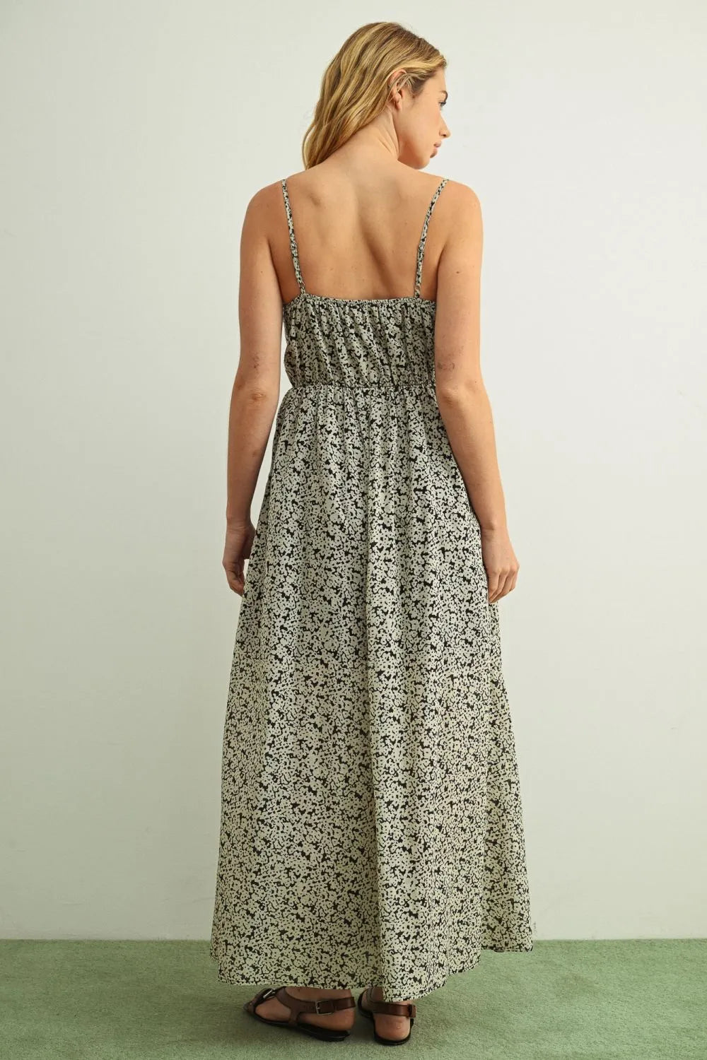 A soft beige floral print maxi summer dress with delicate black patterns and thin spaghetti straps