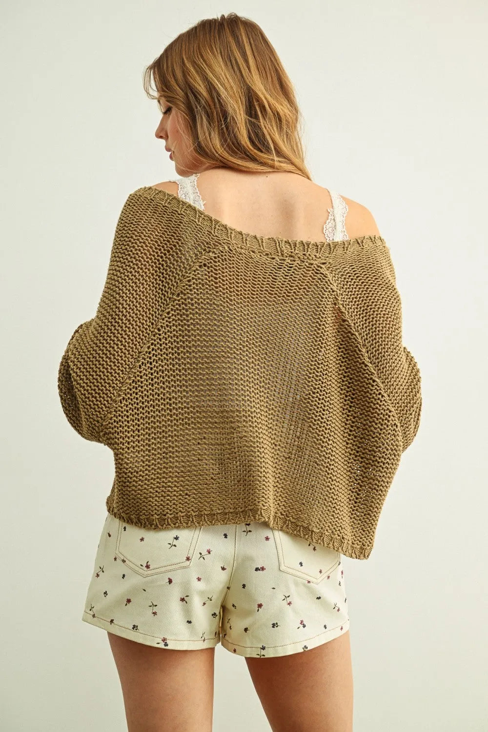 A loose olive green long sleeve cropped cardigan knitted with textured pattern and frayed hem