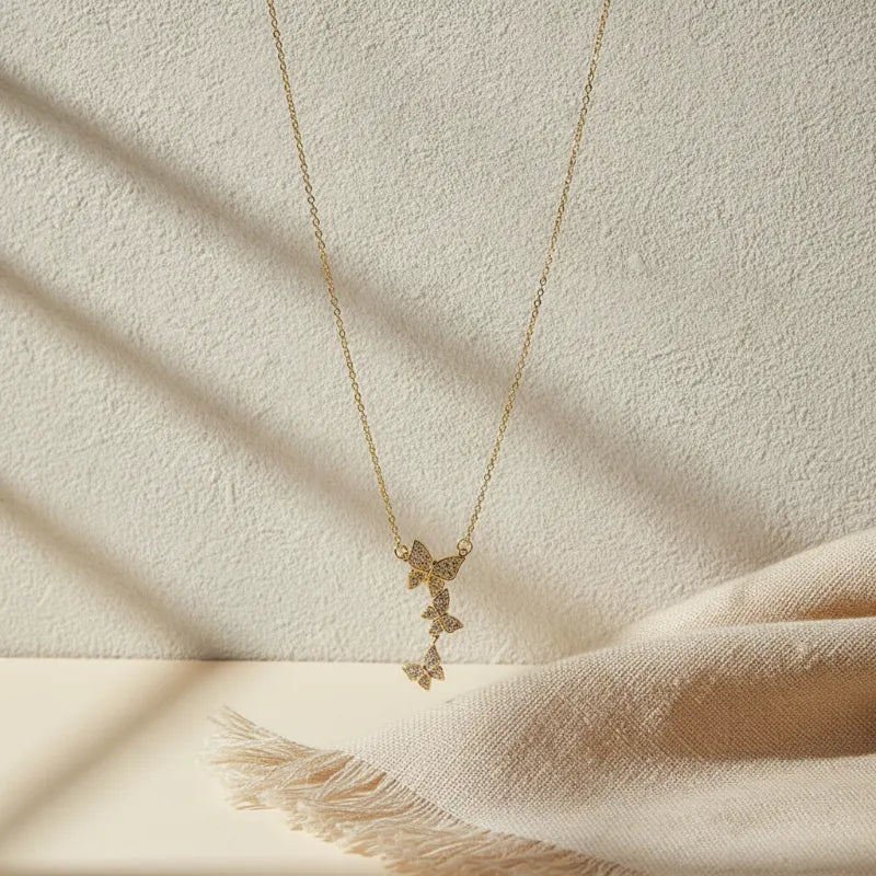 Delicate luxury dainty gold plated necklace with a cascading trio of three butterfly pendants adorned with sparkling stones