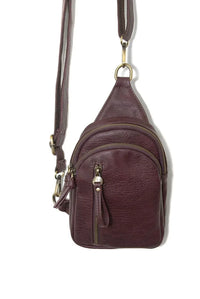 Skyler sling bag is a maroon leather crossbody bag with multiple zippers and a gold-tone metal clasp