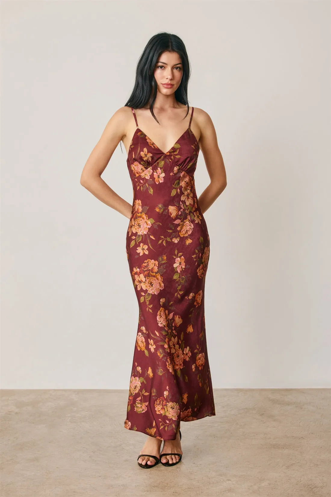A flowing maroon satin slip dress with a floral chevron seam and delicate peach and gold floral pattern, open back detail