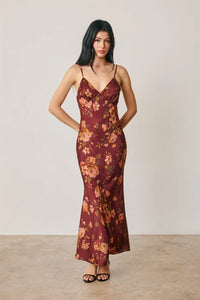 A flowing maroon satin slip dress with a floral chevron seam and delicate peach and gold floral pattern, open back detail
