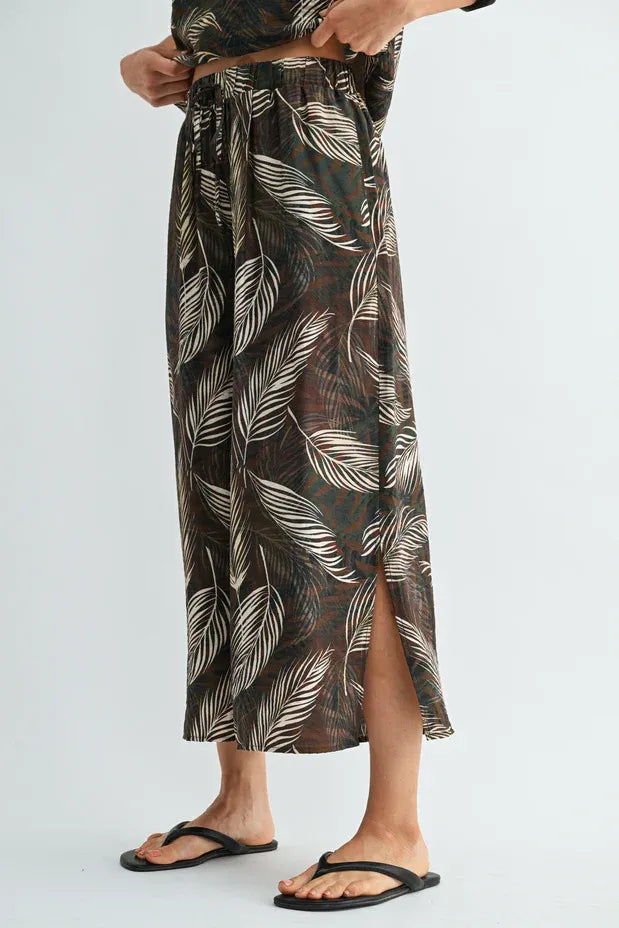 A flowing dark brown leaf print elastic waist maxi skirt with white leaf pattern and side slit