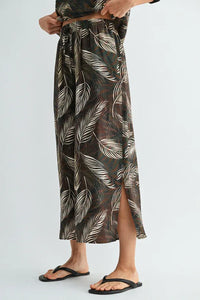 A flowing dark brown leaf print elastic waist maxi skirt with white leaf pattern and side slit