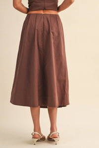 A flowing mid-calf length brown linen pleated waist flare midi skirt with a smooth satin finish and central back zipper