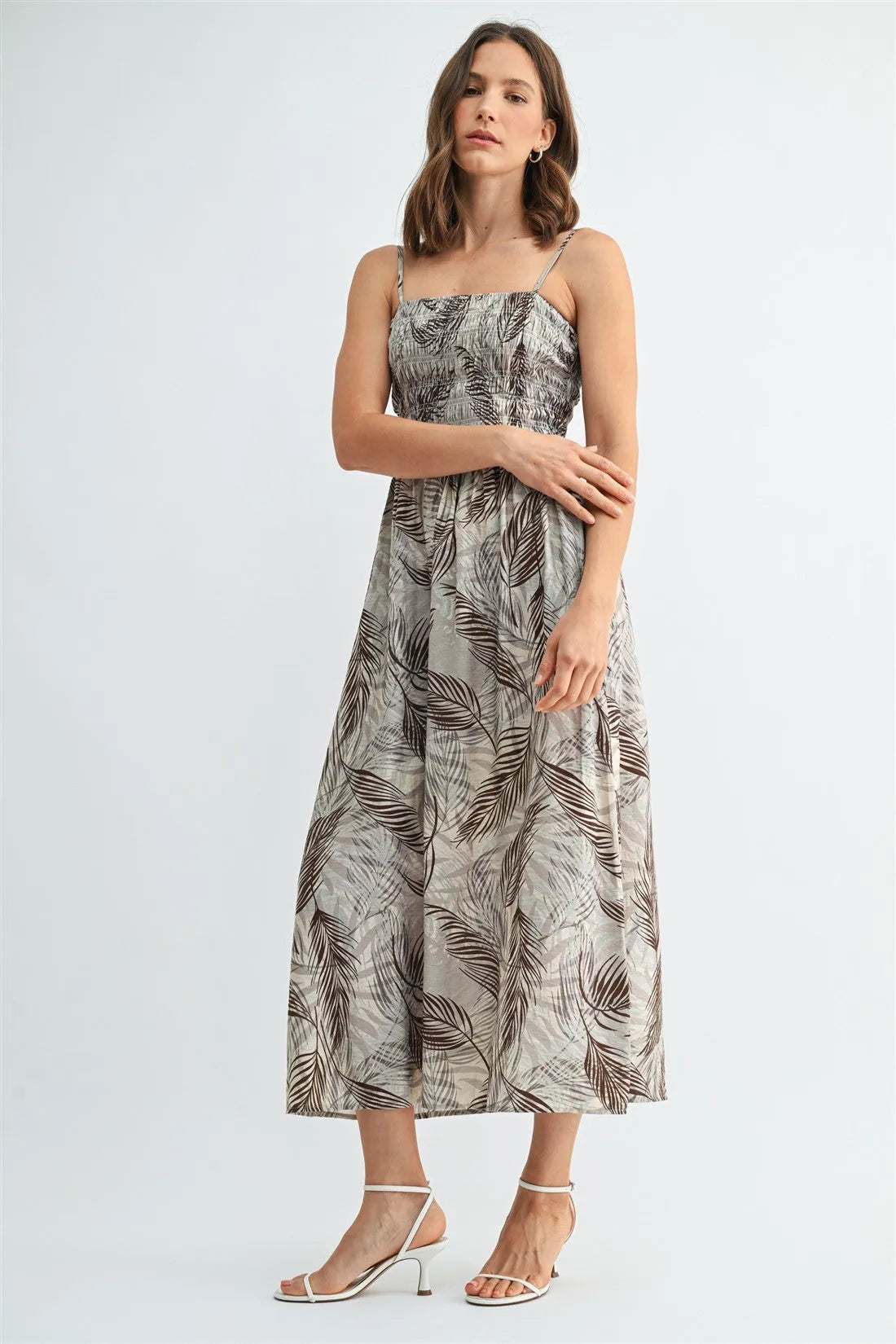 A flowing leaf print smocking midi dress in gray and brown leafy pattern on light beige fabric reaching mid-thigh