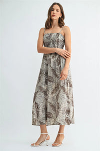 A flowing leaf print smocking midi dress in gray and brown leafy pattern on light beige fabric reaching mid-thigh