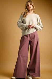 The model wears a light beige long sleeve boat neck top sweater in soft knit with textured weave and off-the-shoulder design