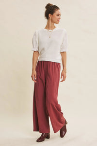 The model wears white ribbed knit top with puffed sleeves paired with step washed wide leg pants
