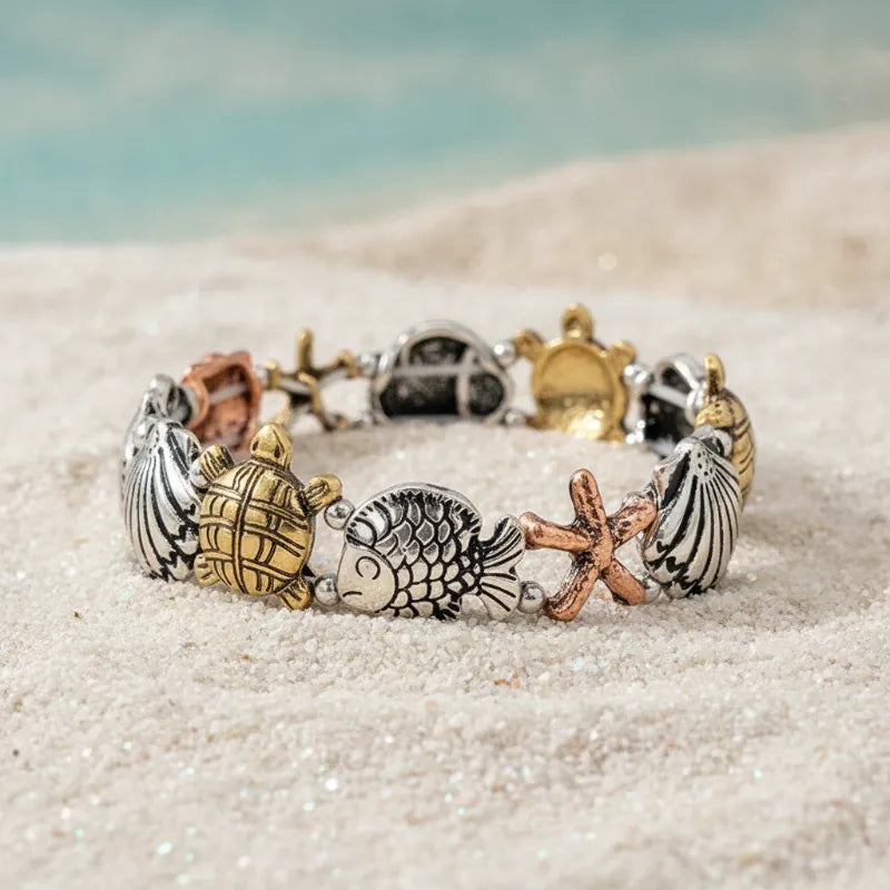 Ocean life stretch bracelet featuring tri-tone sea turtle, starfish, fish, and seashell charms in silver, gold, and copper