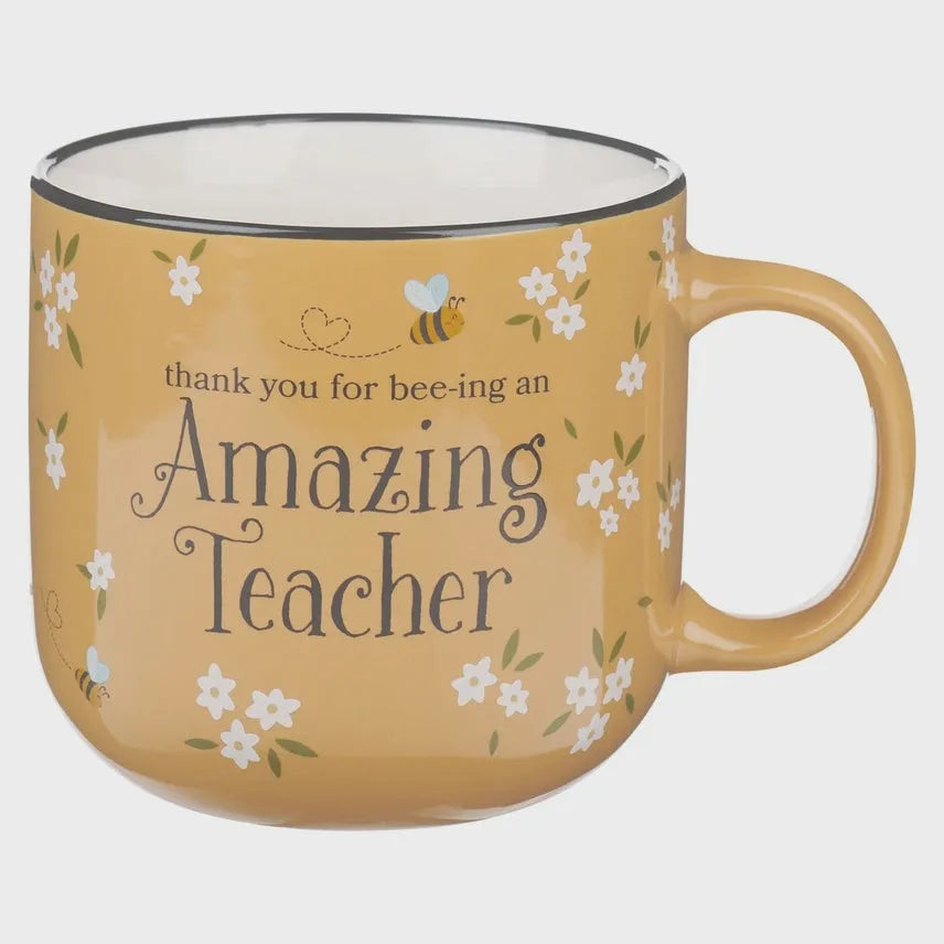 A mustard-yellow ceramic mug amazing teacher with black rim white flowers bees and thank you for bee-ing an amazing teacher text