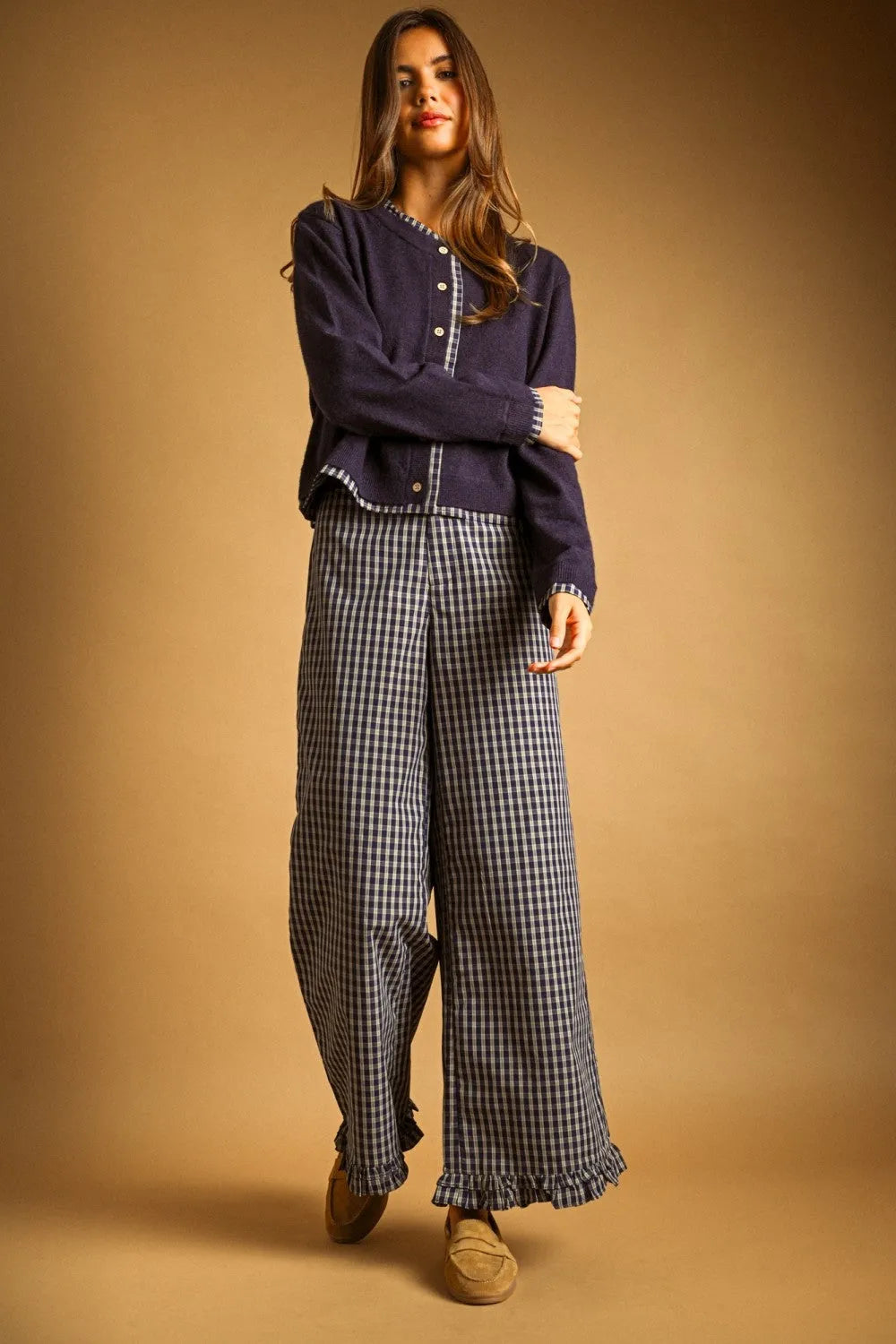A navy blue plaid contrasted button front cardigan with white trim and ruffled hem paired with black and white checkered trousers