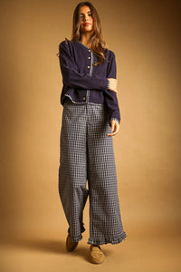 A navy blue plaid contrasted button front cardigan with white trim and ruffled hem paired with black and white checkered trousers