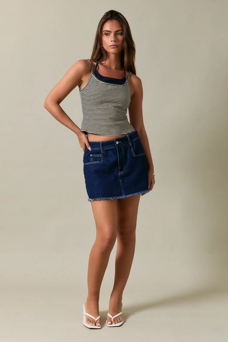 Navy blue denim mini skirt with frayed hem and white stitching paired with two tone halter neckline stripe tank top