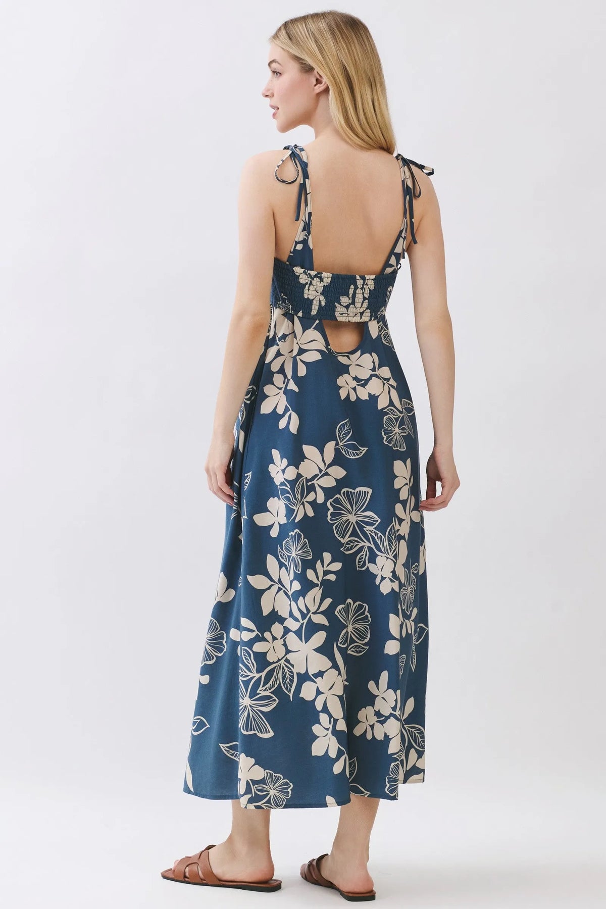 A navy blue floral cami midi dress with cream blossoms featuring adjustable tie straps and a back cutout detail