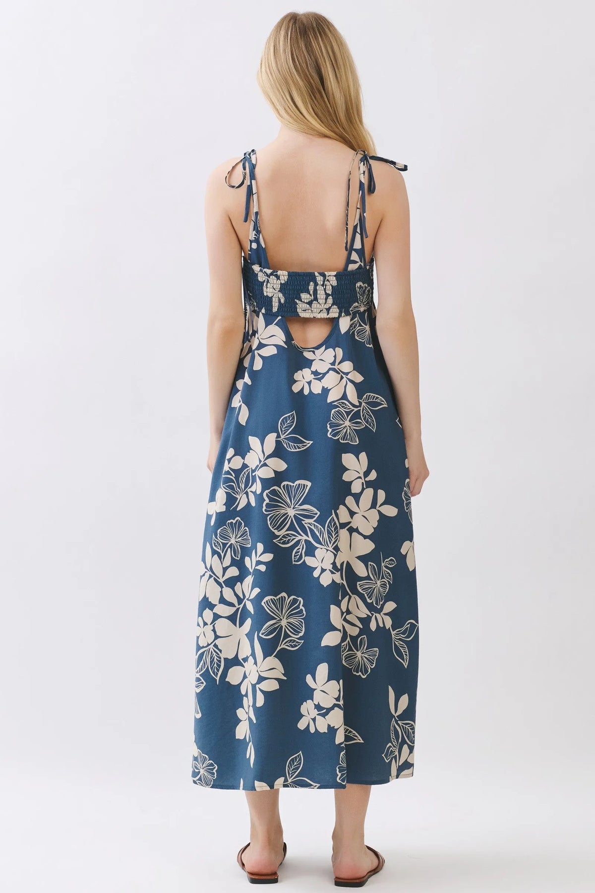 A navy blue floral cami midi dress with white blossoms featuring adjustable tie straps and a back cutout