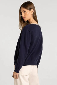 Navy blue knit pippa cardigan with decorative white and black checkered trim along the neckline by thread & supply