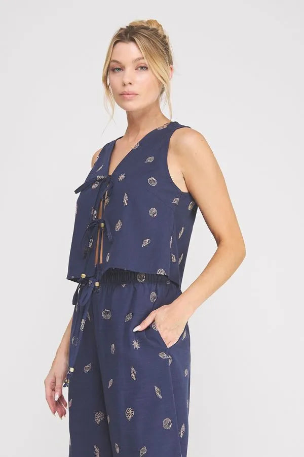 Navy blue sleeveless jumpsuit with seashell lace embroidered woven subtle white leaf and circular pattern v-neck tied front