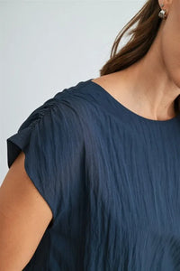 A navy blue soft textured boxy elastic waist blouse with ruched shoulder detailing for stylish comfort