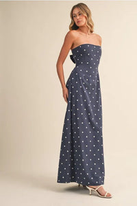 A navy blue polka dot maxi dress with a strapless fitted bodice and bow tie at the waist polka dot tube style