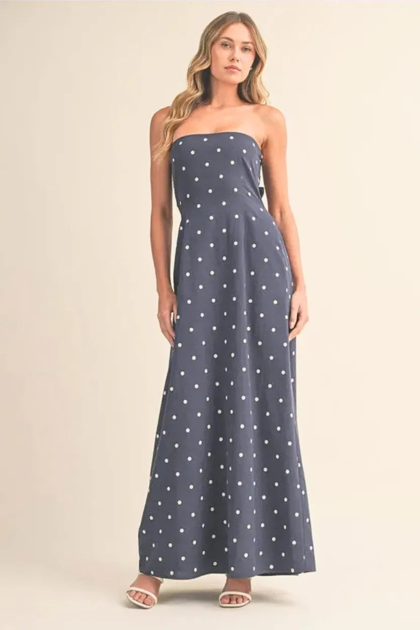 A navy blue strapless polka dot tube maxi dress with tie back detail perfect for elegant summer occasions